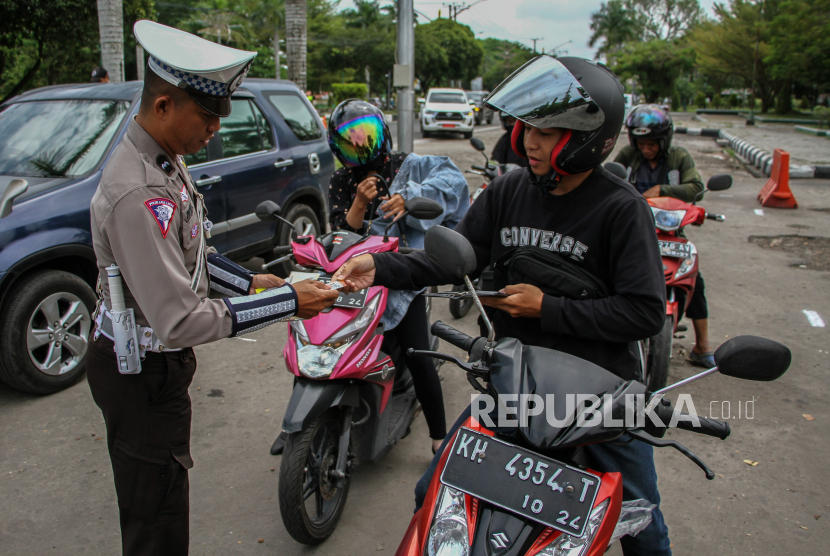 Seorang anggota polisi dari Direktorat Lalu Lintas (Ditlantas) Polda Kalteng memeriksa surat kendaraan bermotor saat operasi kepatuhan pajak kendaraan bermotor di Jalan Yos Sudarso, Palangka Raya, Kalimantan Tengah, Rabu (4/9/2024). Operasi yang dilakukan Badan Pendapatan Daerah (Bapenda) Kalteng bersama Ditlantas Polda Kalteng tersebut bertujuan untuk meningkatkan kedisiplinan masyarakat dalam membayar pajak sekaligus mendongkrak pendapatan daerah. 