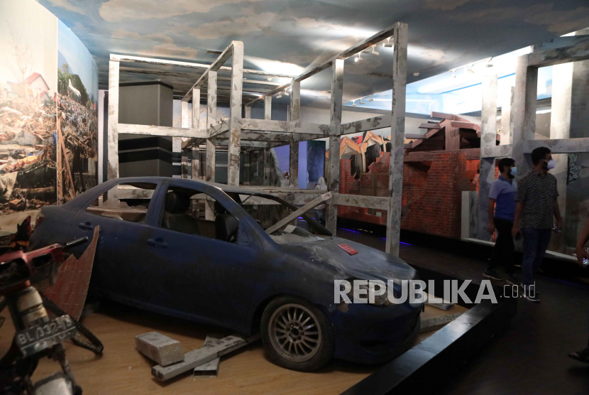 Pengunjung melihat mobil yang hancur saat peninggalan tsunami dipajang di Museum Tsunami di Banda Aceh, Indonesia, 20 Desember 2022. 