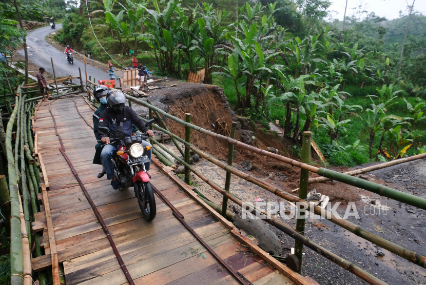 Pengendara sepeda motor melintasi jembatan darurat di lokasi tanah longsor di Wonosobo, Jawa Tengah. Tanah longsor akibat hujan deras mengakibatkan jalan antarkecamatan terputus sehingga warga membuat jembatan darurat yang hanya bisa dilalui sepeda motor dan pejalan kaki (ilustrasi). 