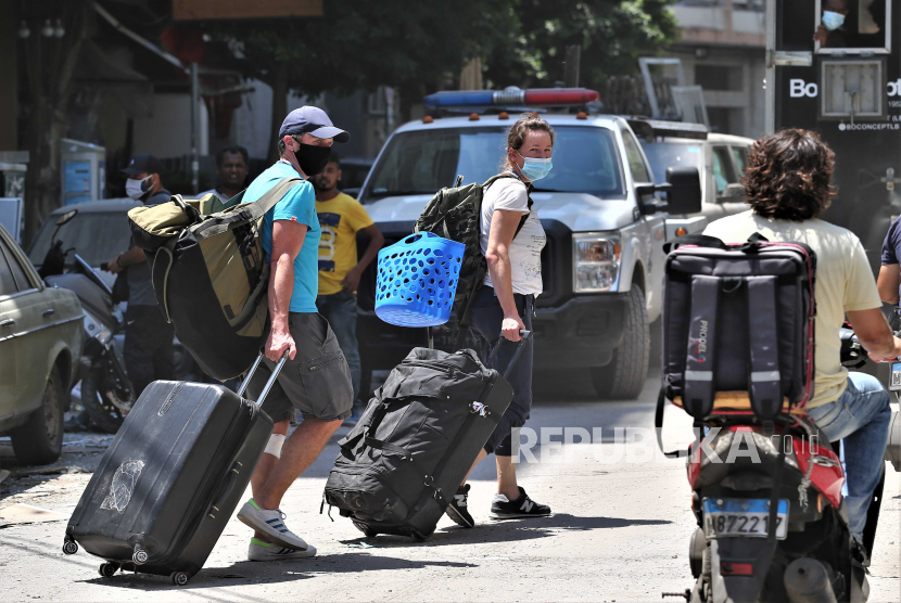 Lebanon di Tepi Jurang Kehancuran Usai Ledakan Dahsyat. Orang-orang berjalan dengan barang-barang mereka setelah evakuasi dari perumahan mereka yang rusak di daerah Mar Mikhael dan Gemayzeh setelah ledakan besar menghancurkan pelabuhan di Beirut pada tanggal 4 Agustus 2020, di Beirut, Lebanon, 05 Agustus 2020. Menurut laporan media, setidaknya 100 orang terbunuh dan lebih dari 4.000 terluka setelah ledakan, yang disebabkan oleh lebih dari 2.500 ton amonium nitrat yang disimpan di sebuah gudang, menghancurkan area pelabuhan pada tanggal 4 Agustus.