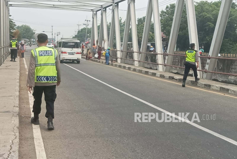 Petugas dari Polsek Sukra Polres Indramayu menertibkan para penyapu koin yang beroperasi di Jembatan Sewo, Kecamatan Sukra, Kabupaten Indramayu, Jumat (5/4/2024). 