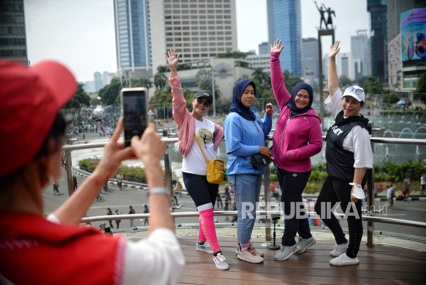 Warga berfoto di Anjungan Halte Bundaran HI saat Hari Bebas Kendaraan Bermotor (HBKB) di kawasan Bundaran Hotel Indonesia, Jakarta. IDI sepakat pencabutan PPKM akan tetapi dengan sejumlah catatan.