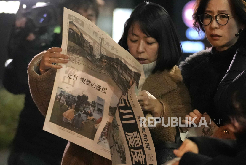 Masyarakat Tokyo membaca edisi ekstra koran Yomiuri Shimbun yang melaporkan soal gempa dan tsunami di Jepang, Senin (1/1/2024).