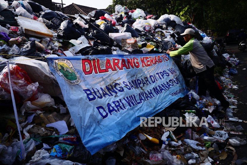 Petugas memasang kembali spanduk larangan membuang sampah setelah sempat terkubur oleh umpukan sampah menggunung di TPS Jalan Guntursari Wetan, Buah Batu Bandung.