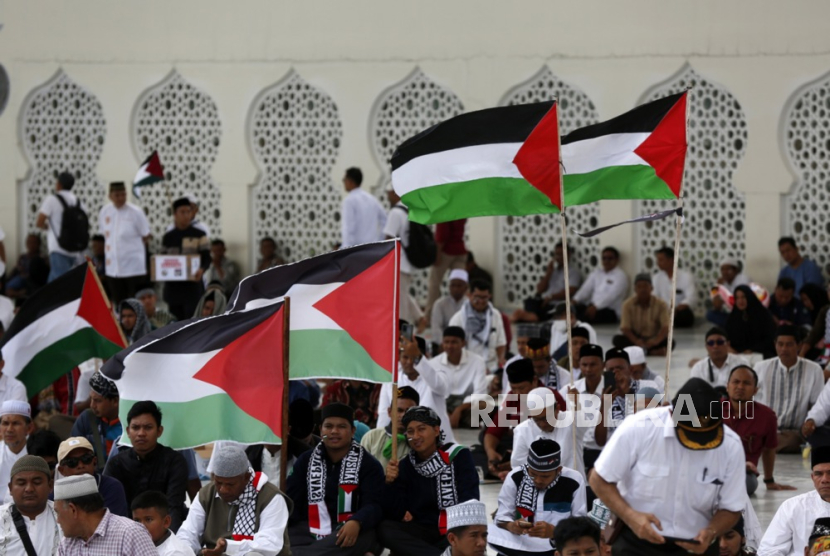 Para pengunjuk rasa memegang bendera berkumpul untuk mendukung warga Palestina.