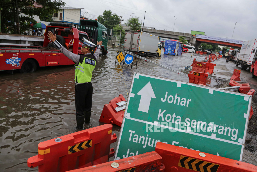 Polis mengatur lalu lintas kendaraan yang macet akibat banjir yang merendam jalur pantura di Jalan Kaligawe Raya, Semarang, Jawa Tengah.
