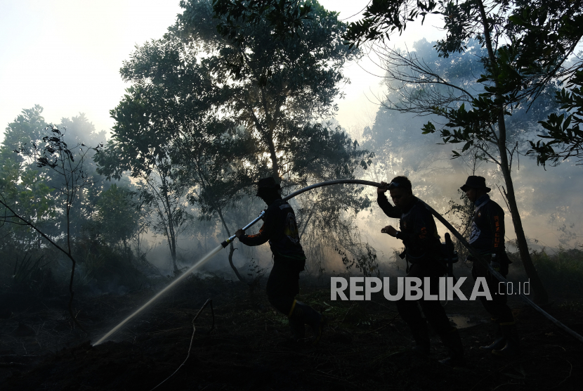 Tiga petugas kepolisian melakukan pembasahan pada lokasi kebakaran hutan dan lahan (karhutla) ilustrasi 
