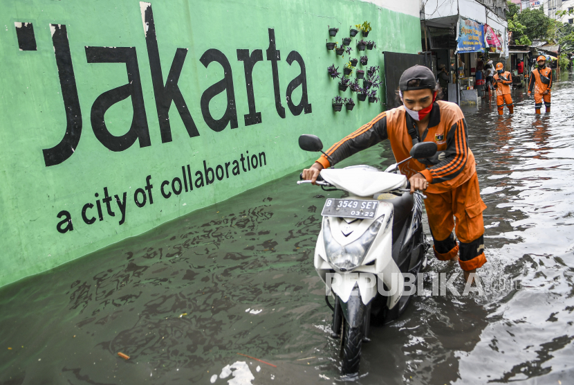 Petugas Penanganan Prasarana dan Sarana Umum (PPSU) menuntun sepeda motor ketika banjir menggenangi kawasan Jakarta Selatan, Senin (25/1/2021). Banjir di sejumlah wilayah Ibu Kota disebabkan intensitas hujan yang tinggi serta buruknya drainase. ANTARA FOTO/M Risyal Hidayat/aww.