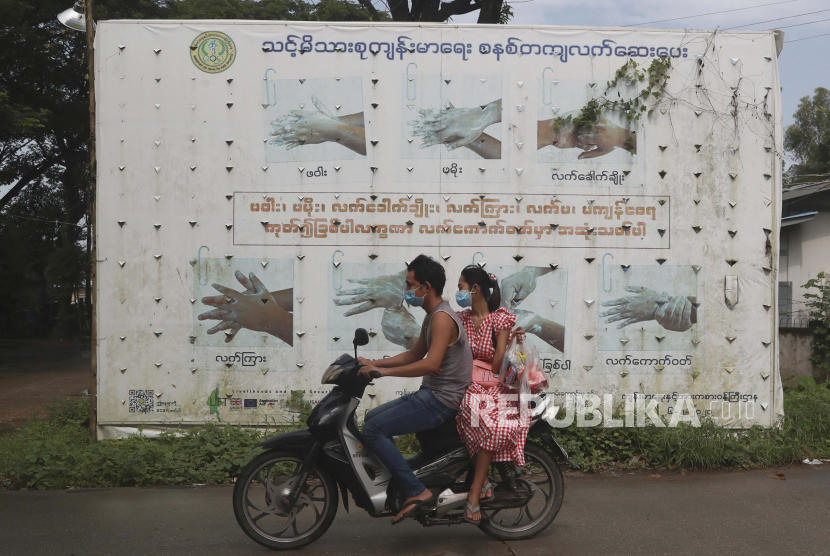Orang-orang yang memakai masker wajah untuk membantu mengekang penyebaran virus corona mengendarai sepeda motor melewati papan iklan kampanye informasi publik Kementerian Kesehatan tentang mencuci tangan yang benar di kota Shwe Pyi Thar di Yangon, Myanmar, Rabu, 28 Juli 2021.