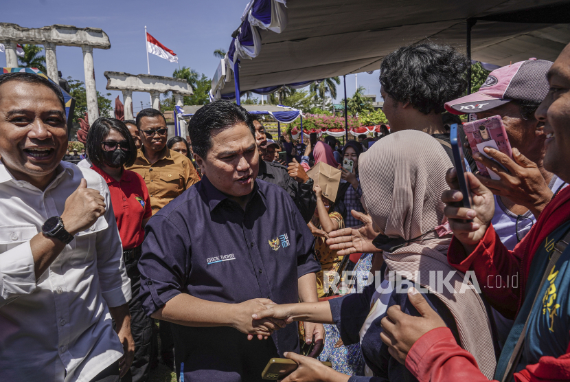 Menteri BUMN Erick Thohir (tengah) bersama Wali kota Surabaya Eri Cahyadi (kiri) menyapa warga saat meninjau Pasar Murah BUMN di kawasan Monumen Tugu Pahlawan, Surabaya, Jawa Timur, Minggu (13/8/2023). Program yang menyalurkan tiga ribu paket sembako kepada masyarakat tersebut bertujuan untuk memastikan ketersediaan bahan pokok dengan harga terjangkau. 