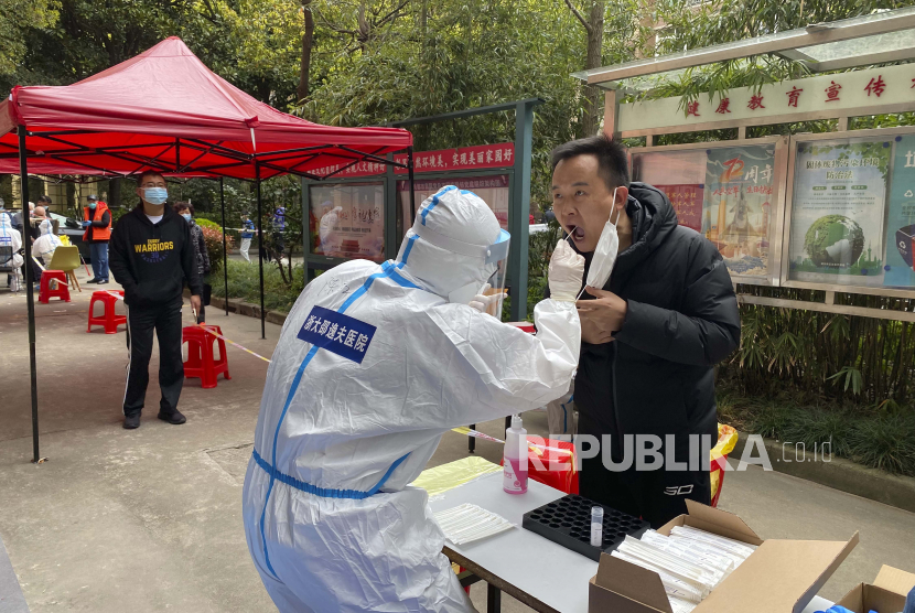 Dalam foto yang dirilis oleh Kantor Berita Xinhua, seorang pekerja medis dari Provinsi Zhejiang mengambil sampel swab dari seorang penduduk untuk tes asam nukleat di tempat pengujian COVID-19 di Distrik Pudong, Shanghai, Tiongkok timur, Senin, 28 Maret 2022. 