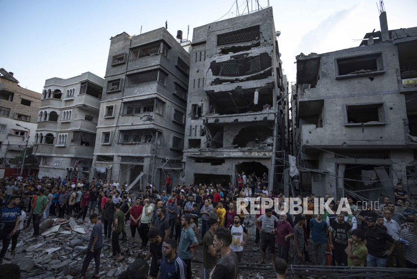Warga Palestina menyaksikan orang lain yang mencari korban luka di reruntuhan bangunan tempat tinggal yang hancur akibat serangan udara Israel, Selasa, 10 Oktober 2023. 