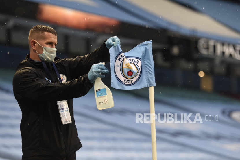 Petugas kebersihan mengangkat bendera Manchester City.