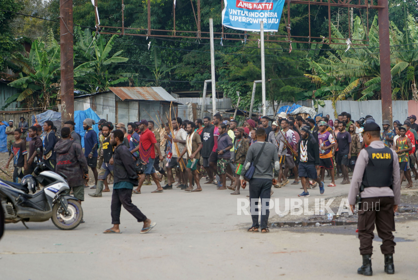 Sejumlah warga membawa senjata panah berjalan usai kerusuhan massa di Papua. (Ilustrasi)