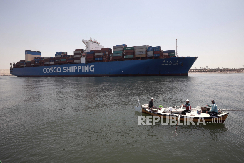 Sebuah kapal kontainer melewati Terusan Suez saat nelayan menggulung jala mereka di Ismalia, Mesir, 27 Mei 2021 (dikeluarkan 28 Mei 2021).
