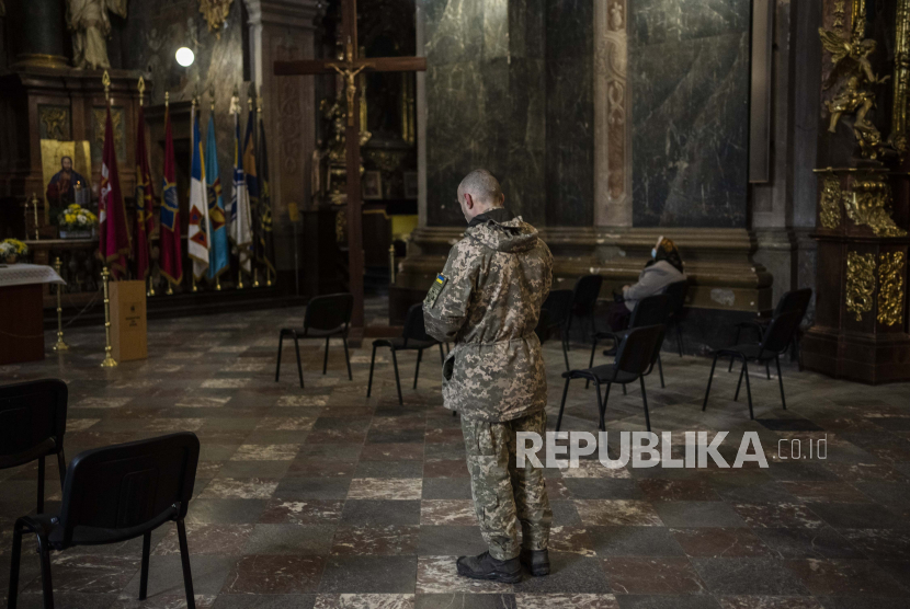 Seorang pria Ukraina mengenakan pakaian militer berdoa di dalam Gereja Saints Peter and Paul Garrison di Lviv, Ukraina barat, Ahad, 6 Maret 2022. Sejumlah pasukan militer Inggris yang masih aktif telah melakukan perjalanan ke Ukraina untuk berperang melawan pasukan Rusia.