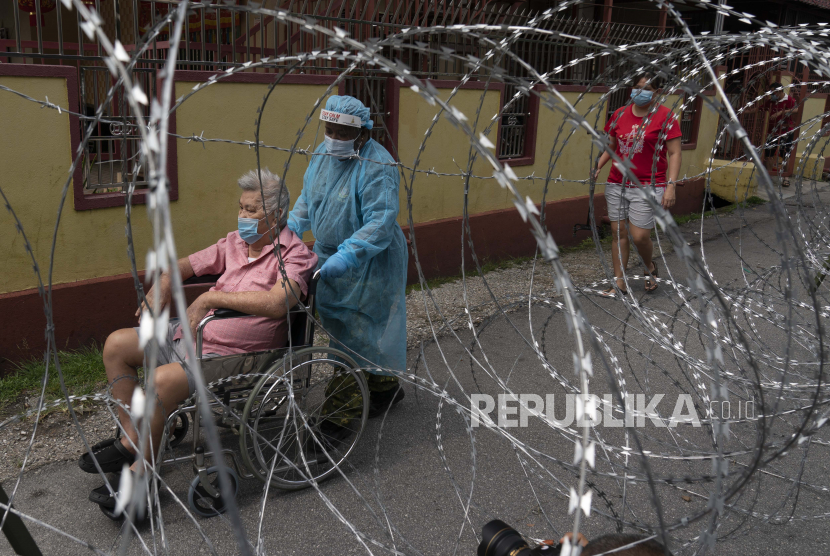 Seorang petugas kesehatan mendorong seorang kakek yang berada kursi roda di sebelah kawat berduri di area lockdown Selayang Baru, di luar Kuala Lumpur, Malaysia, Ahad (26/4). Lockdown tersebut dilakukan untuk memungkinkan aparat berwenang dalam melakukan penyaringan dan membantu mencegah penyebaran coronavirus
