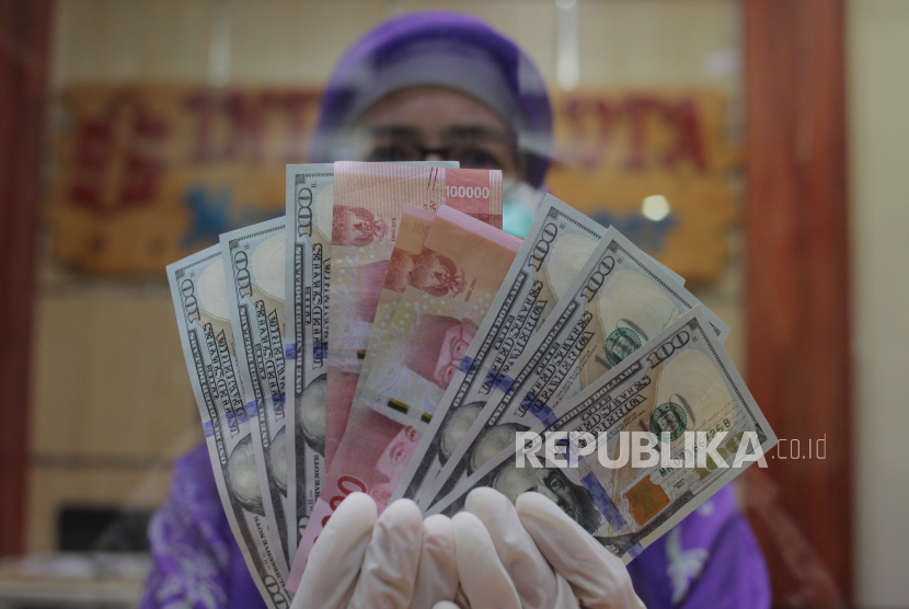 Petugas menunjukkan uang rupiah dan dolar AS di salah satu gerai penukaran mata uang asing di Jakarta. ilustrasi