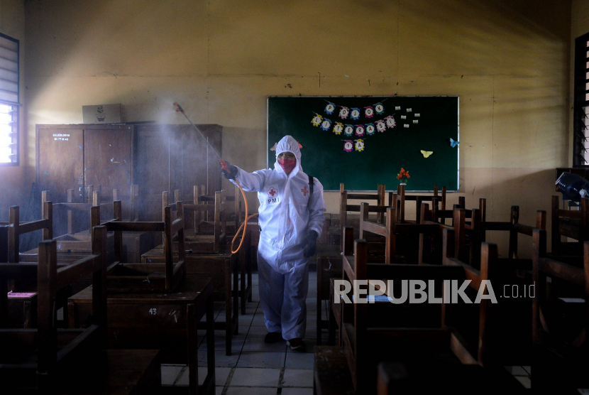 Petugas Palang Merah Indonesia (PMI) melakukan penyemprotan disinfektan di lingkungan sekolah. (ilustrasi).