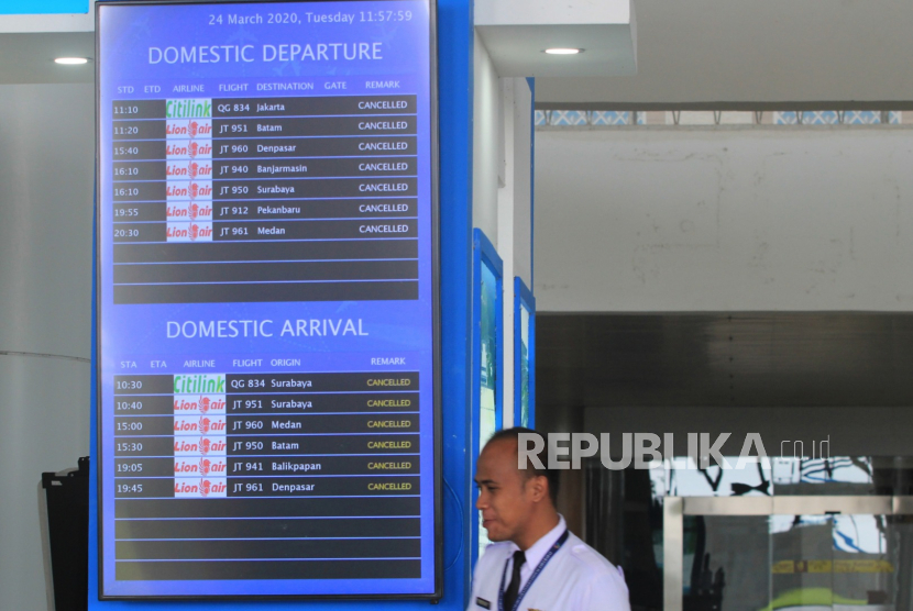 Petugas melintas di samping layar informasi  penerbangan di Bandara Internasional Kertajati, Majalengka, Jawa Barat, Selasa (24/3/2020).