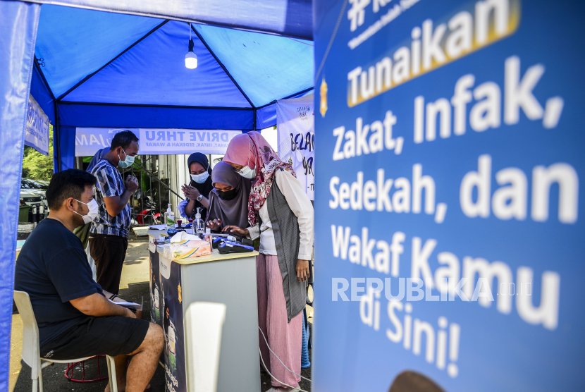 Muzaki saat membayar zakat kepada petugas di depan Masjid Al Azhar, Jakarta, Selasa (11/5). Alquran menegaskan perintah menegakkan shalat dan membayar zakat paling tidak di 32 ayat.