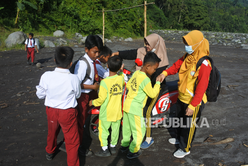 Guru SDN Jugosari 03 Eri Eliyawati dan Lilik Kusnilawati disambut sejumlah murid di pinggir Sungai Regoyo, Desa Jugosari, Candipuro, Lumajang, Jawa Timur.