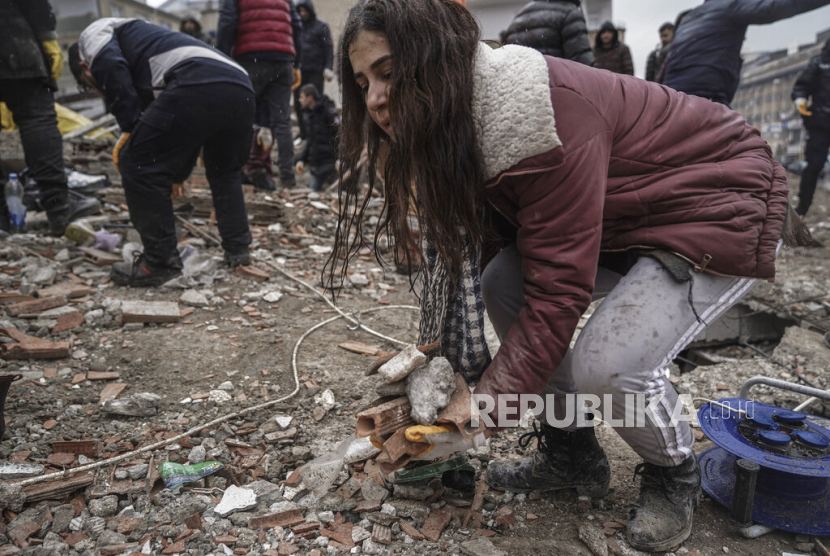 Seorang wanita muda memindahkan puing-puing dari bangunan yang hancur saat dia mencari korban gempa dengan tim penyelamat di Gaziantep, Turki, Senin (6/2/2023). Gempa kuat telah merobohkan beberapa bangunan di tenggara Turki dan Suriah dan dikhawatirkan banyak korban jiwa. Produk Menstruasi untuk Korban Gempa Turki-Suriah Kerap Luput dari Paket Bantuan