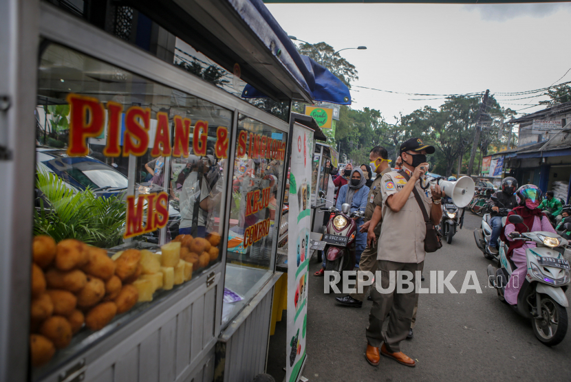 Petugas Satpol PP mengimbau pengunjung untuk menggunakan masker dan menjaga jarak di Pasar Lama, Kota Tangerang, Banten, Senin (4/5/2020). Pemerintah Kota Tangerang melakukan penegasan pada PSBB tahap dua dengan menugaskan petugas di tempat rawan keramaian guna mencegah penyebaran COVID-19