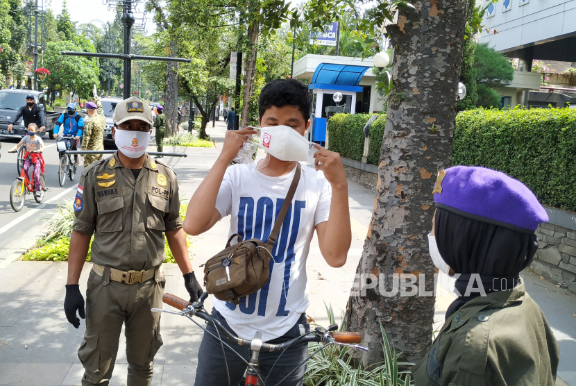 Pertugas gabungan melakukan operasi yustisi protokol Covid-19, di kawasan Cikapayang, Jl Ir H Djuanda, Kota Bandung, Ahad (27/9). Dalam operasi itu, warga yang tidak membawa masker diberikan masker, meski demikian kepada pelanggar tetap diberikan sangsi.