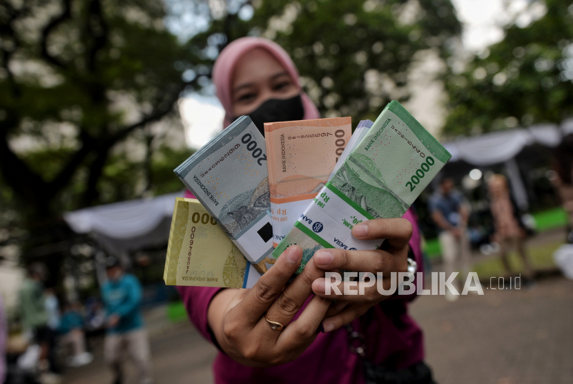 Warga menunjukan uang pecahan baru di area Parkir Timur Gelora Bung Karno (GBK) Jakarta, Ahad (9/4/2023). Pemberian THR sebagai bentuk berbagi kebahagiaan kepada anak-anak saudara, tetangga dan anak-anak sudah menjadi tradisi momen lebaran. 