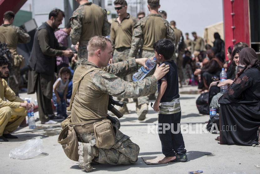 Bantu Evakuasi, Belanda Tambah Pasukan di Afghanistan. Dalam gambar yang disediakan oleh Korps Marinir AS ini, seorang Marinir dengan Unit Ekspedisi Marinir (MEU) ke-24 memberikan air bersih kepada seorang anak selama evakuasi di Bandara Internasional Hamid Karzai di Kabul, Afghanistan, Jumat, 20 Agustus 2021.