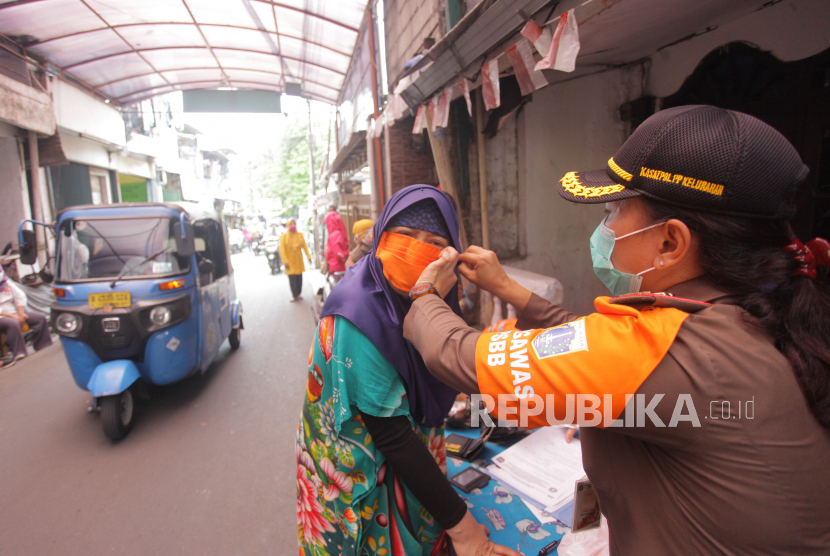 Petugas memakaikan masker kepada warga yang melanggar protokol kesehatan (ilustrasi). Pemerintah Kabupaten Sigi, Provinsi Sulawesi Tengah, memperketat protokol kesehatan di obyek wisata.