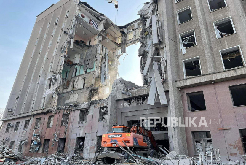 Sebuah foto selebaran yang dirilis oleh layanan pers Layanan Darurat Negara Ukraina pada 30 Maret 2022 menunjukkan layanan darurat melakukan operasi pencarian dan penyelamatan di gedung administrasi negara regional yang rusak di Mykolaiv, Ukraina. 