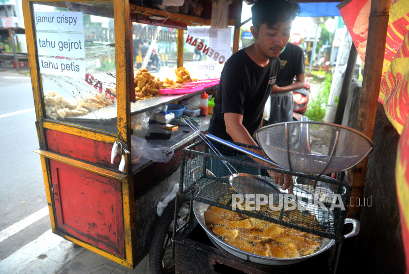 Penjual menggoreng gorengan di Yogyakarta, Ahad (20/3/2022). Penjual gorengan langsung merasakan dampak sejak kebijakan untuk menghentikan harga eceran tertinggi (HET) untuk minyak goreng. Harga gorengan mulai menyesuaikan, semula Rp 2 ribu untuk tiga menjadi Rp 2.500 untuk tiga buah. Meskipun sudah penyesuaian harga, penjual masih menanggung turunnya laba hingga 50 persen.