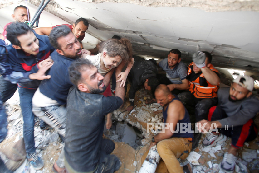 Tim penyelamat membawa seorang gadis saat mereka mencari korban di tengah puing-puing di lokasi serangan udara Israel, di Kota Gaza 16 Mei 2021.