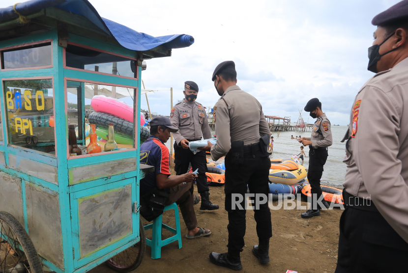 Personel Polres Indramayu memberi masker kepada pedagang saat razia protokol kesehatan (prokes) di objek wisata pantai Karangsong, Indramayu, Jawa Barat (ilustrasi)