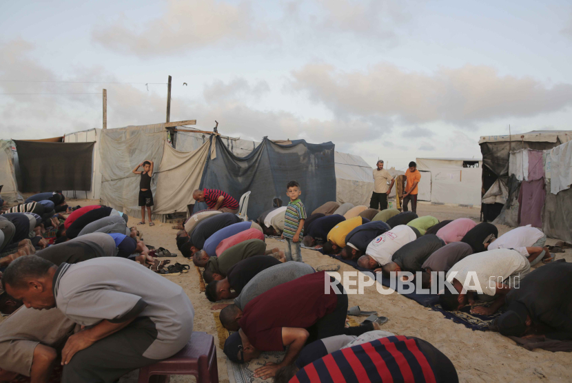 Warga Palestina yang mengungsi akibat serangan udara dan darat Israel di Jalur Gaza melaksanakan sholat Idul Adha di kamp tenda darurat Khan Younis, Gaza, Ahad, 16 Juni 2024.