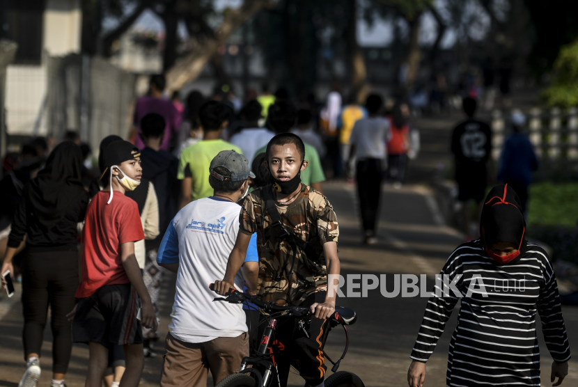 Warga tidak menggunakan masker secara benar saat berolahraga pada Hari Bebas Kendaraan Bermotor (HBKB) atau Car Free Day (CFD) di Jalan Inspeksi BKT, Jakarta, Ahad (12/7/2020). 