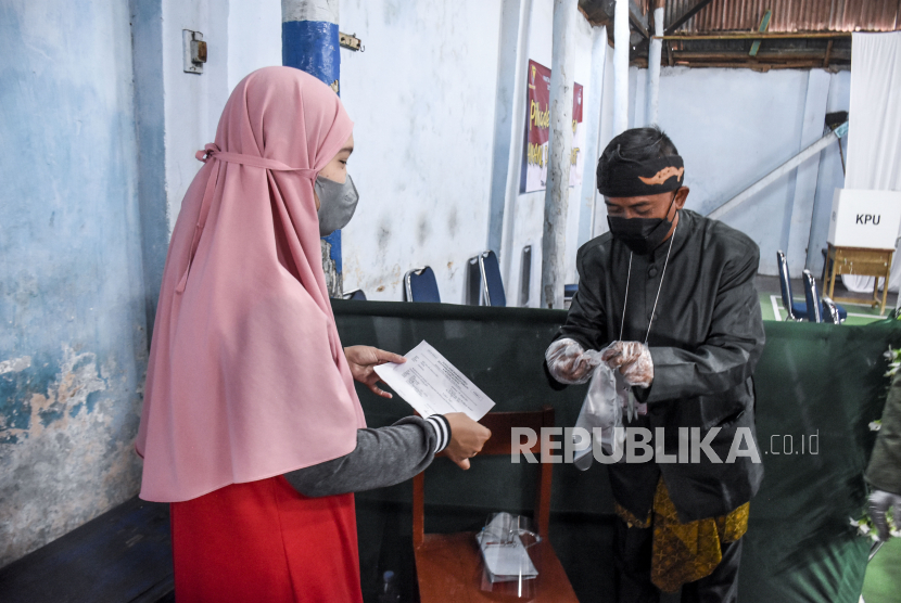 Petugas memberikan sarung tangan plastik ke warga sebelum menggunakan hak pilihnya pada Pemilihan Kepala Desa (Pilkades) serentak. (Ilustrasi)