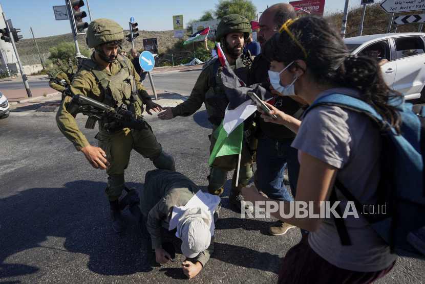  Informan Israel di Tepi Barat Buat Warga Palestina Kian Terkekang. Foto:  Warga Palestina dan aktivis perdamaian Israel melarikan diri dari gas air mata yang ditembakkan oleh pasukan keamanan Israel, selama demonstrasi menentang pemukiman Yahudi Tepi Barat, dekat kota Salfit, Tepi Barat, Rabu, 27 Juli 2022.