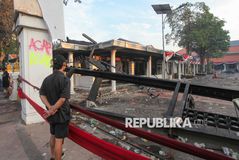 Warga menyaksikan sebagian bangunan Gedung Negara Grahadi yang terbakar dalam aksi massa di Surabaya, Jawa Timur, Ahad (31/8/2025).