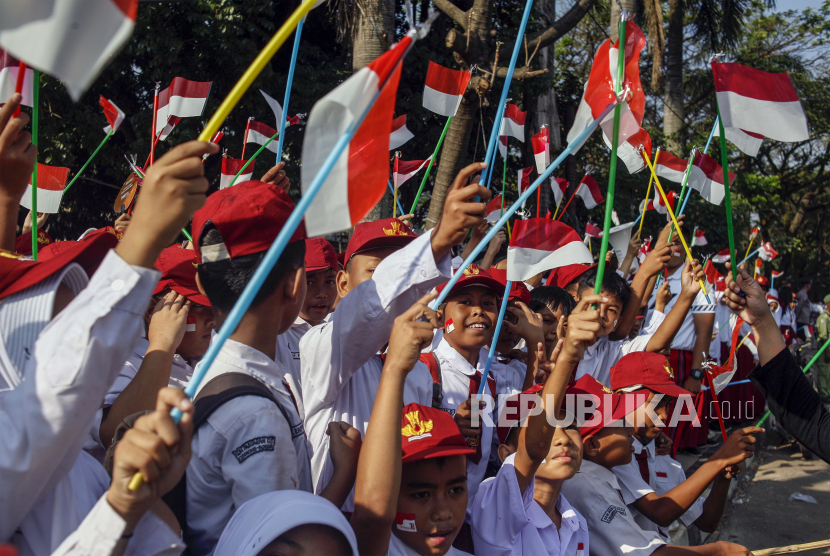 Sejumlah siswa SD mengibarkan bendera Merah Putih di pinggir Jalan Raya Bogor, Cibinong, Kabupaten Bogor, Jawa Barat, Selasa (1/8/2023), untuk menyambut HUT Kemerdekaan Indonesia.
