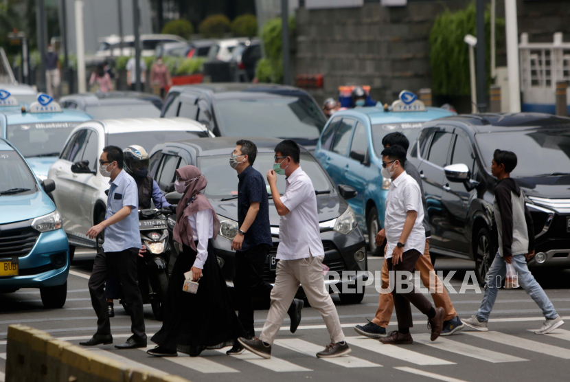Orang Indonesia berjalan melintasi jalan utama di Jakarta. Ekonom menilai krisis ekonomi 2023 bisa lebih parah dari 1998 dan 2008
