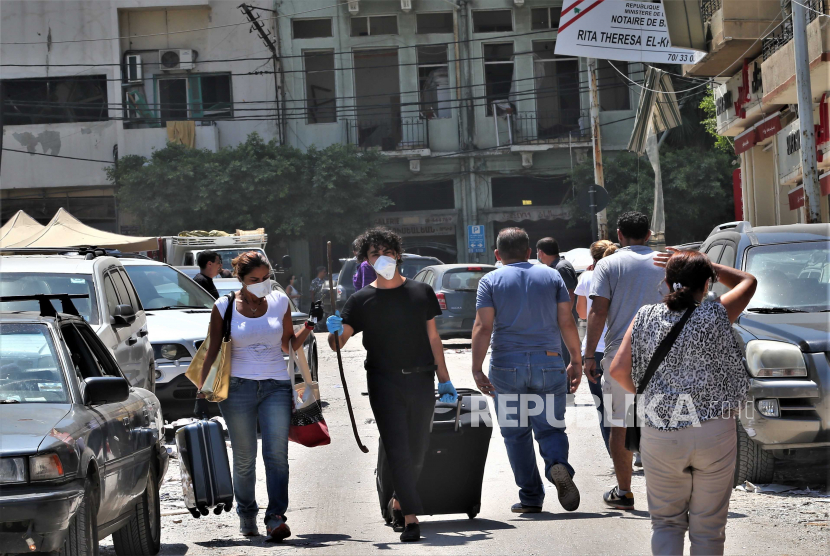 Orang-orang berjalan dengan barang-barang mereka setelah evakuasi dari perumahan mereka yang rusak di daerah Mar Mikhael dan Gemayzeh setelah ledakan besar menghancurkan pelabuhan di Beirut pada tanggal 4 Agustus 2020, di Beirut, Lebanon, 05 Agustus 2020. Menurut laporan media, setidaknya 100 orang terbunuh dan lebih dari 4.000 terluka setelah ledakan, yang disebabkan oleh lebih dari 2.500 ton amonium nitrat yang disimpan di sebuah gudang, menghancurkan area pelabuhan pada tanggal 4 Agustus. 