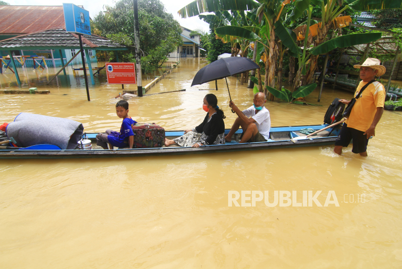 Sejumlah warga melintasi jalan yang terendam banjir dengan perahu (ilustrasi)