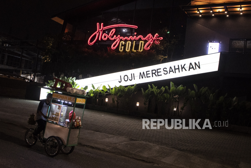 Pedagang melintasi outlet Holywing di Kelapa Gading, Jakarta Utara, Senin (27/6/2022).