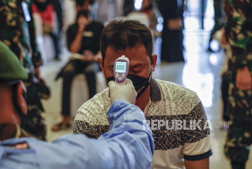 Seorang petugas kesehatan memeriksa suhu tubuh seseorang selama kampanye vaksinasi yang diselenggarakan oleh Polri dan TNI di Markas Brimob di Depok, Jawa Barat, Indonesia, 20 Oktober 2021. 
