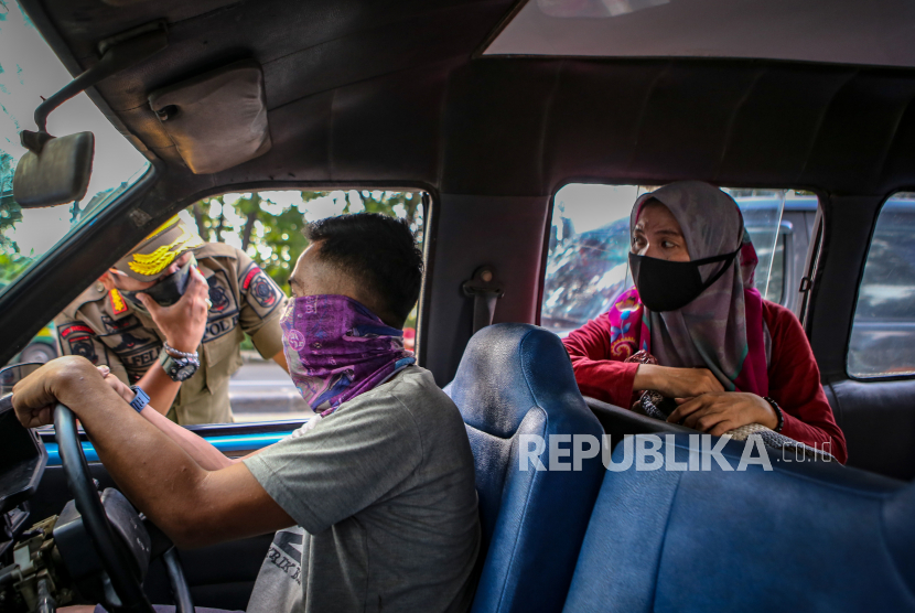 Petugas Satpol PP memberikan sosialisasi penerapan PSBB kepada pengendara di Jalan Daan Mogot, Tangerang, Banten, Selasa (14/4/2020). Menteri Kesehatan menyetujui menerapkan Pembatasan Sosial Berskala Besar (PSBB) di Tangerang Raya yang akan mulai diterapkan pada Sabtu (18/4) dalam rangka percepatan penanganan COVID-19
