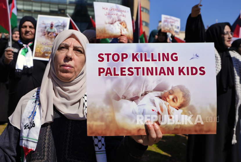 Seorang wanita Palestina yang tinggal di Lebanon memegang plakat saat protes menuntut gencatan senjata dan mendukung warga Palestina di Jalur Gaza, di depan markas besar Komisi Ekonomi dan Sosial PBB 