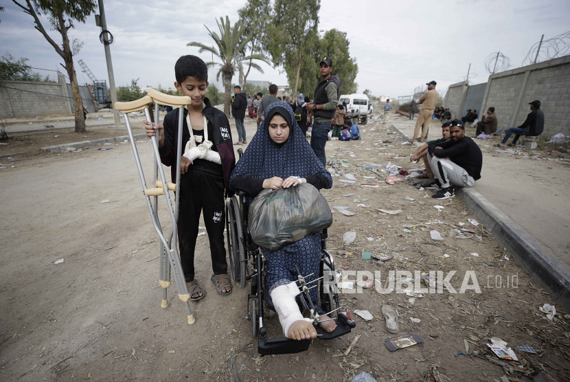 Seorang anak laki-laki dan seorang wanita Palestina yang terluka menyeberang dari Jalur Gaza utara ke Jalur Gaza selatan di sepanjang jalan Salah Al Din di Jalur Gaza tengah, 25 November 2023. 